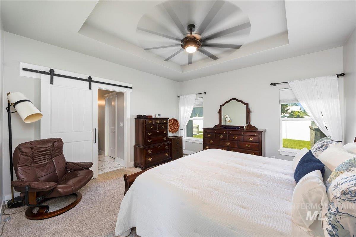 1436 Jump Street Twin Falls, ID 83301 - Photo 14 of 35 Bedroom with a tray ceiling, a barn door, a ceiling fan, and carpet flooring