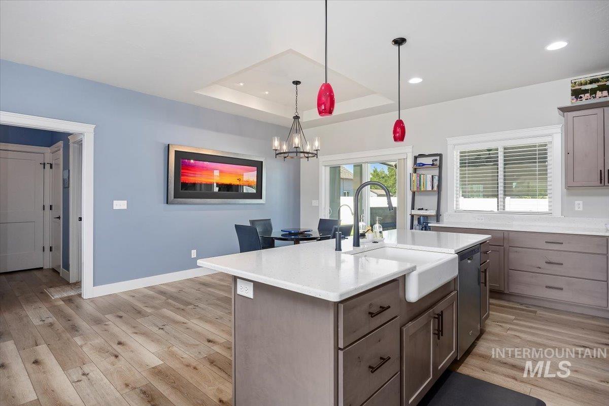 1436 Jump Street Twin Falls, ID 83301 - Photo 7 of 35 Kitchen featuring decorative light fixtures, a raised ceiling, light stone countertops, light wood finished floors, and an island with sink