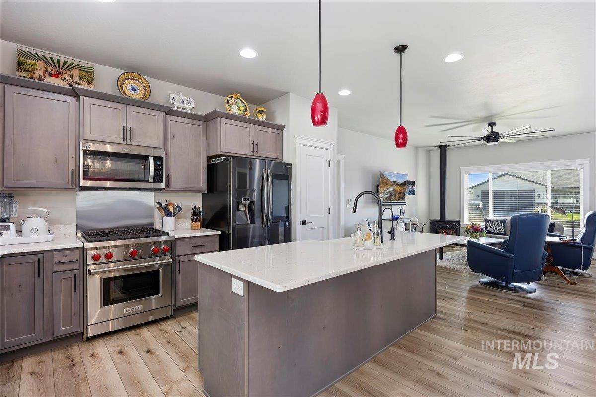 1436 Jump Street Twin Falls, ID 83301 - Photo 9 of 35 Kitchen featuring appliances with stainless steel finishes, ceiling fan, hanging light fixtures, dark brown cabinets, and a center island with sink