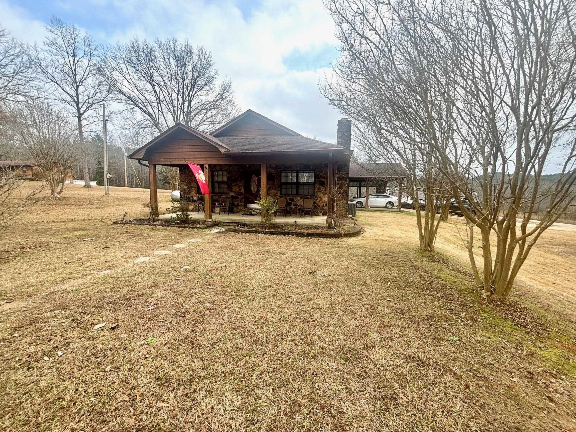 View of front of property featuring a chimney, a porch, and a front lawn