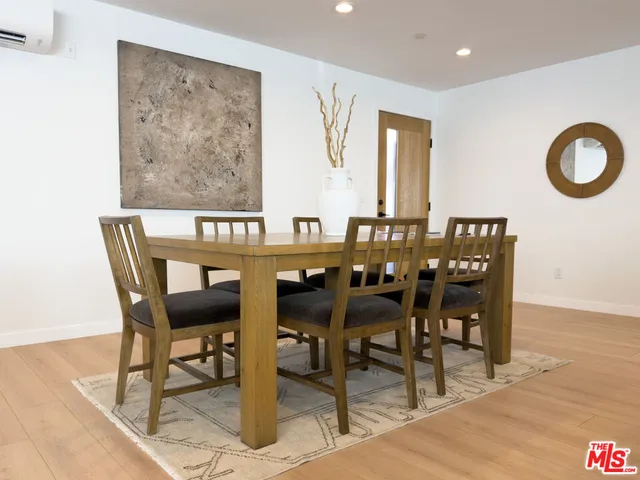 a view of a dining room and livingroom with furniture wooden floor a rug a painting and a chandelier