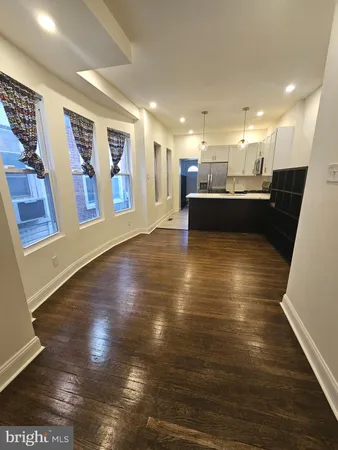 a view of a living room and kitchen with stainless steel appliances wooden floors
