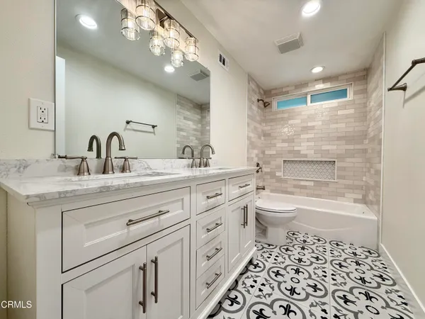 a bathroom with a granite countertop sink a toilet and a bathtub