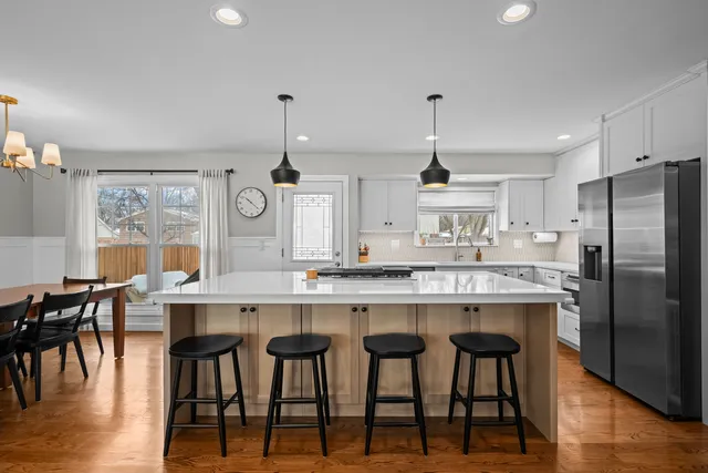 a kitchen with kitchen island granite countertop a table chairs stove and wooden floor