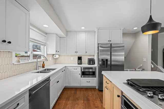 a kitchen with a sink stainless steel appliances and white cabinets