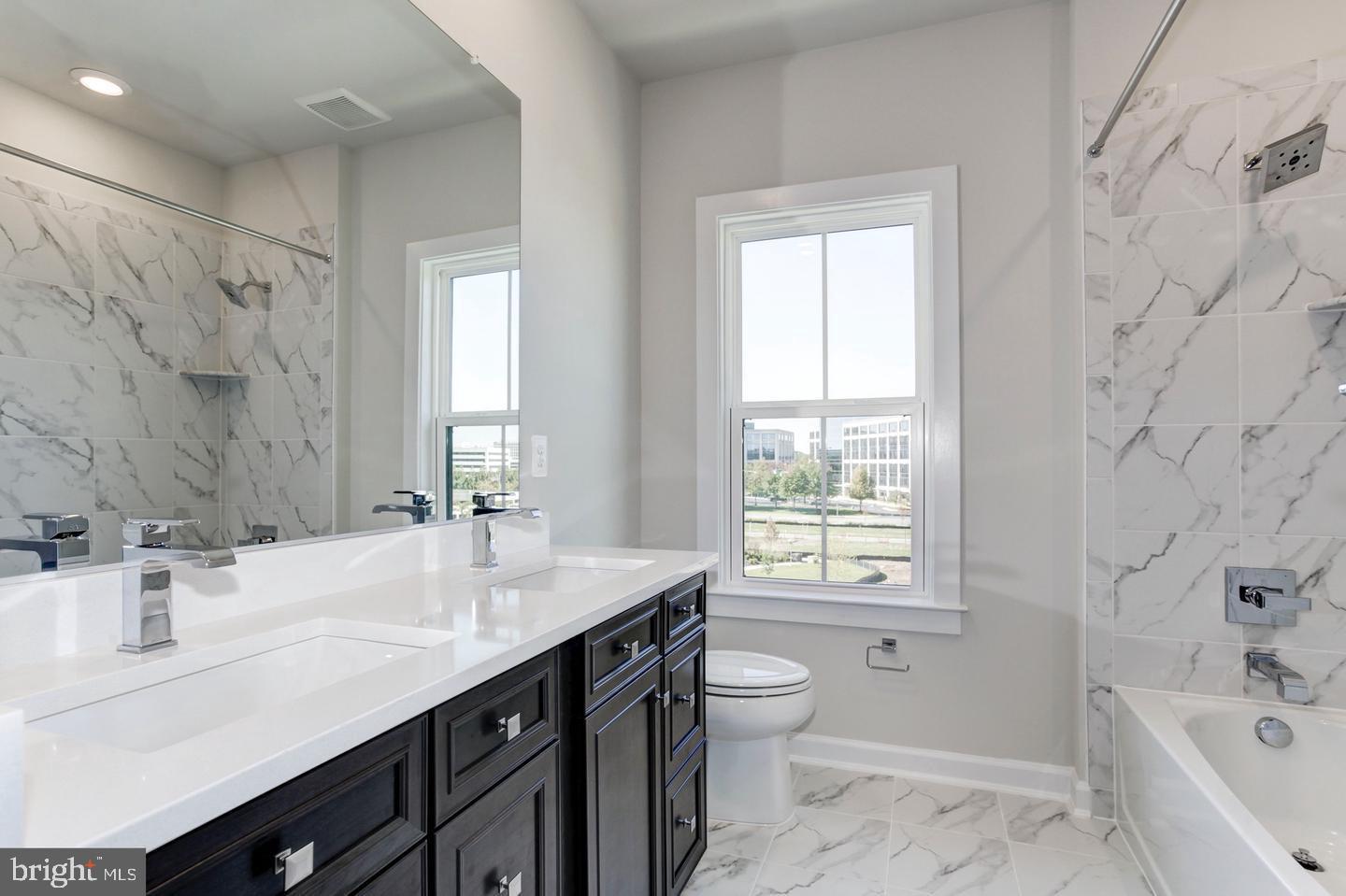 12923 Sunrise Ridge Alley Herndon, VA 20171 - Photo 17 of 25 a bathroom with a granite countertop sink toilet a large mirror a bathtub and window