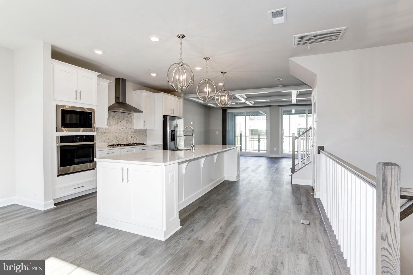 12923 Sunrise Ridge Alley Herndon, VA 20171 - Photo 2 of 25 a large kitchen with stainless steel appliances kitchen island a large counter top and wooden floors