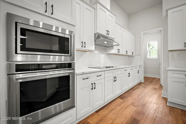 a kitchen with stainless steel appliances white cabinets a stove top oven and sink