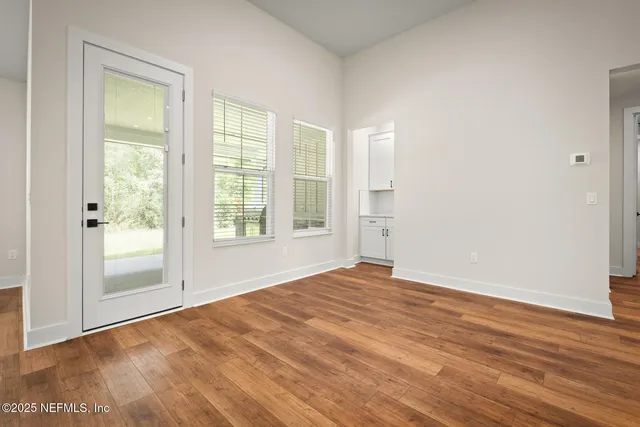 a view of an empty room with wooden floor and a window