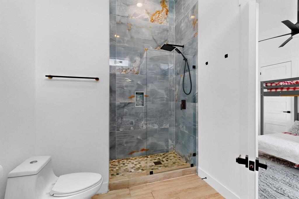 3946 North Cresthaven Road Dallas, TX 75209 - Photo 26 of 38 Contemporary bathroom featuring a spacious glass-enclosed shower with large format wall tiles and a pebble floor