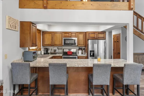 a kitchen with granite countertop a table chairs microwave and cabinets