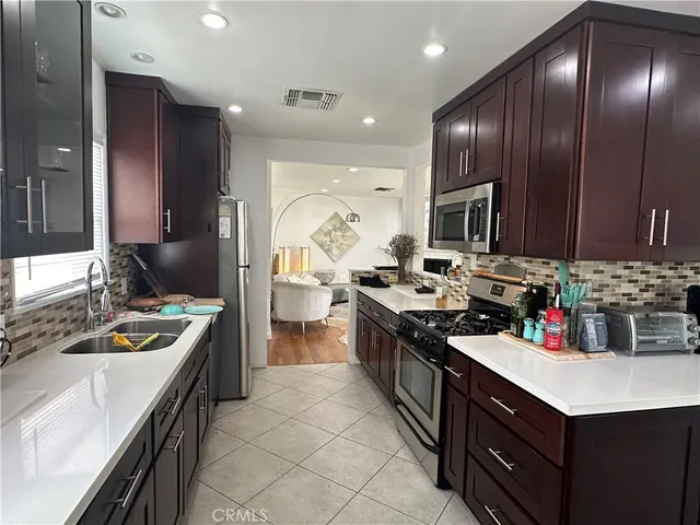 a kitchen with a stove a sink a refrigerator and chairs