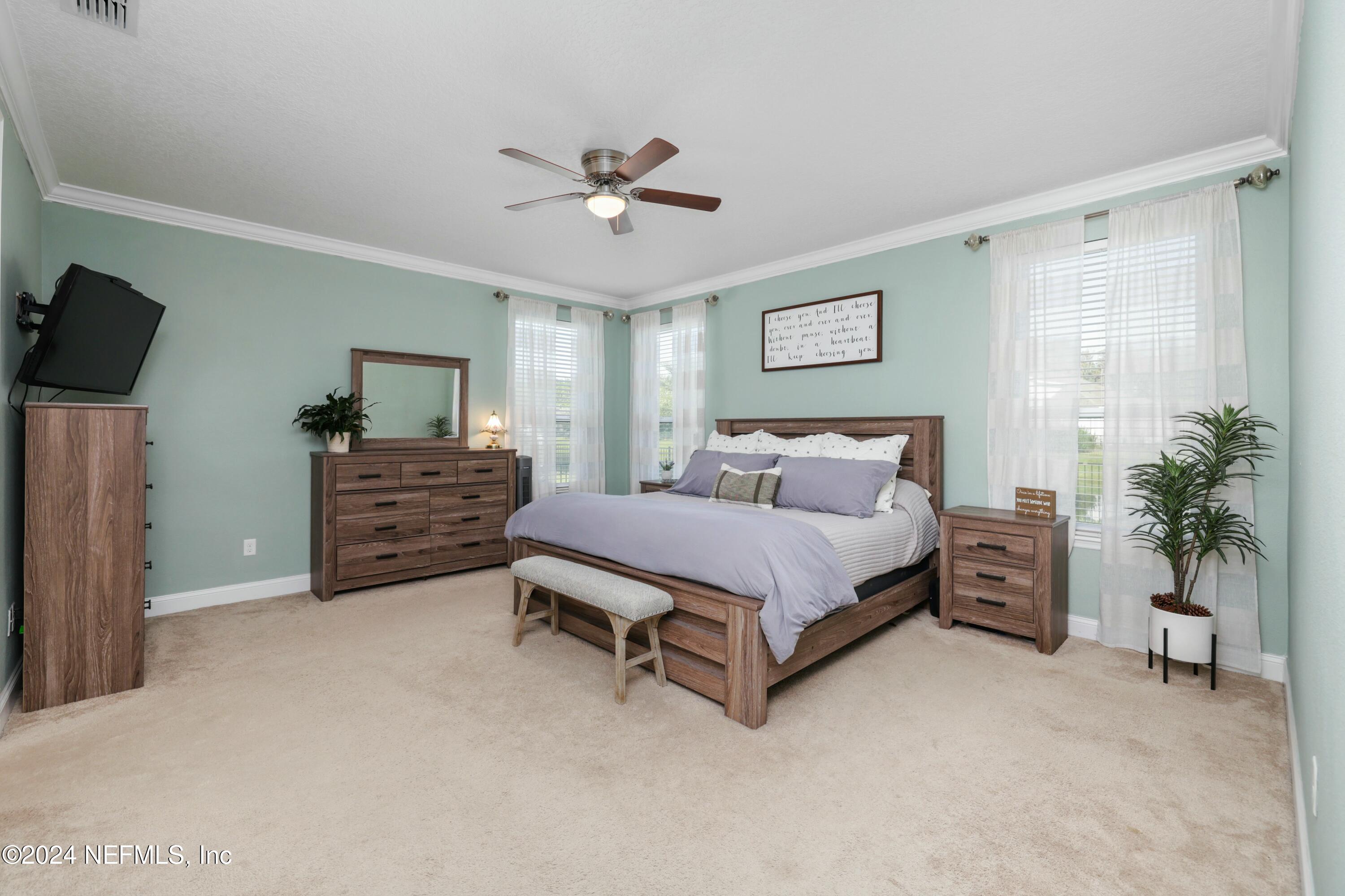 404 St Kitts Loop St. Augustine, FL 32092 - Photo 19 of 68 a spacious bedroom with a bed and a chandelier