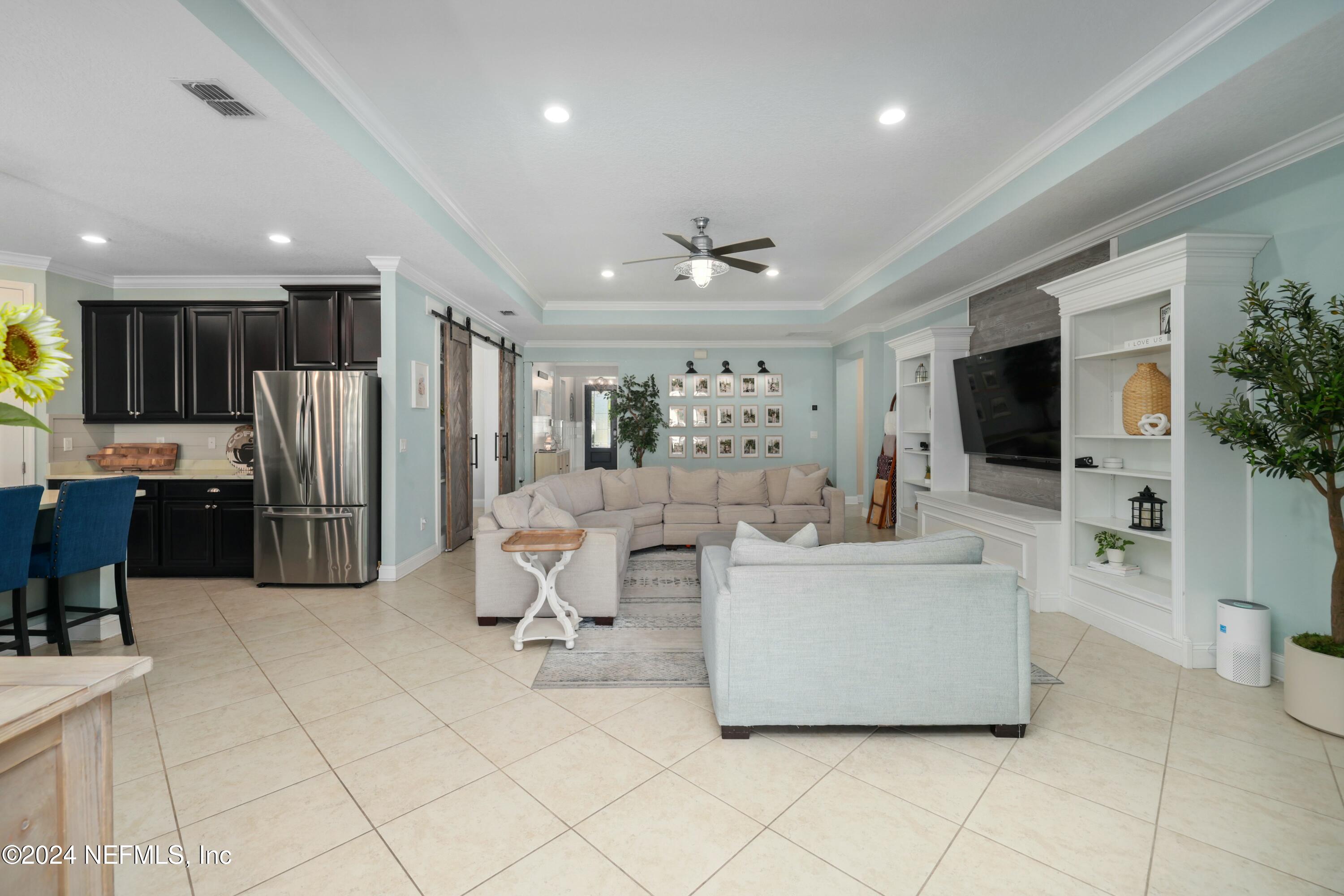 404 St Kitts Loop St. Augustine, FL 32092 - Photo 22 of 68 a living room with furniture a flat screen tv and a refrigerator