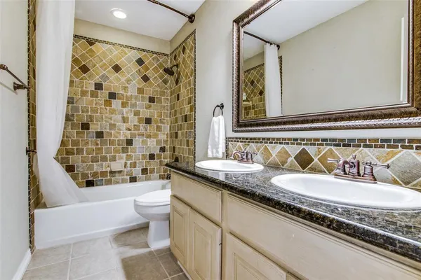 a bathroom with a granite countertop bathtub sink vanity mirror and toilet