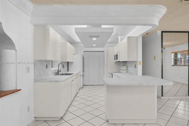 a large white kitchen with a sink and dishwasher