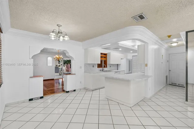 a large white kitchen with a sink and cabinets