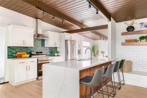 a kitchen with stainless steel appliances kitchen island granite countertop a stove a sink and a refrigerator