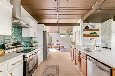 a kitchen with stainless steel appliances kitchen island granite countertop a sink a counter space cabinets and a window