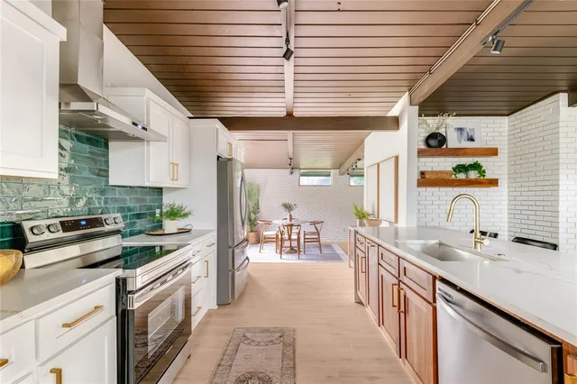 a kitchen with stainless steel appliances kitchen island granite countertop a sink a counter space cabinets and a window