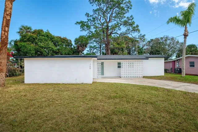 front view of house with a yard and a large tree