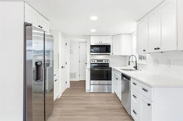 a kitchen with white cabinets and stainless steel appliances