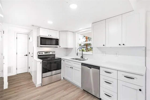a kitchen with white cabinets and appliances