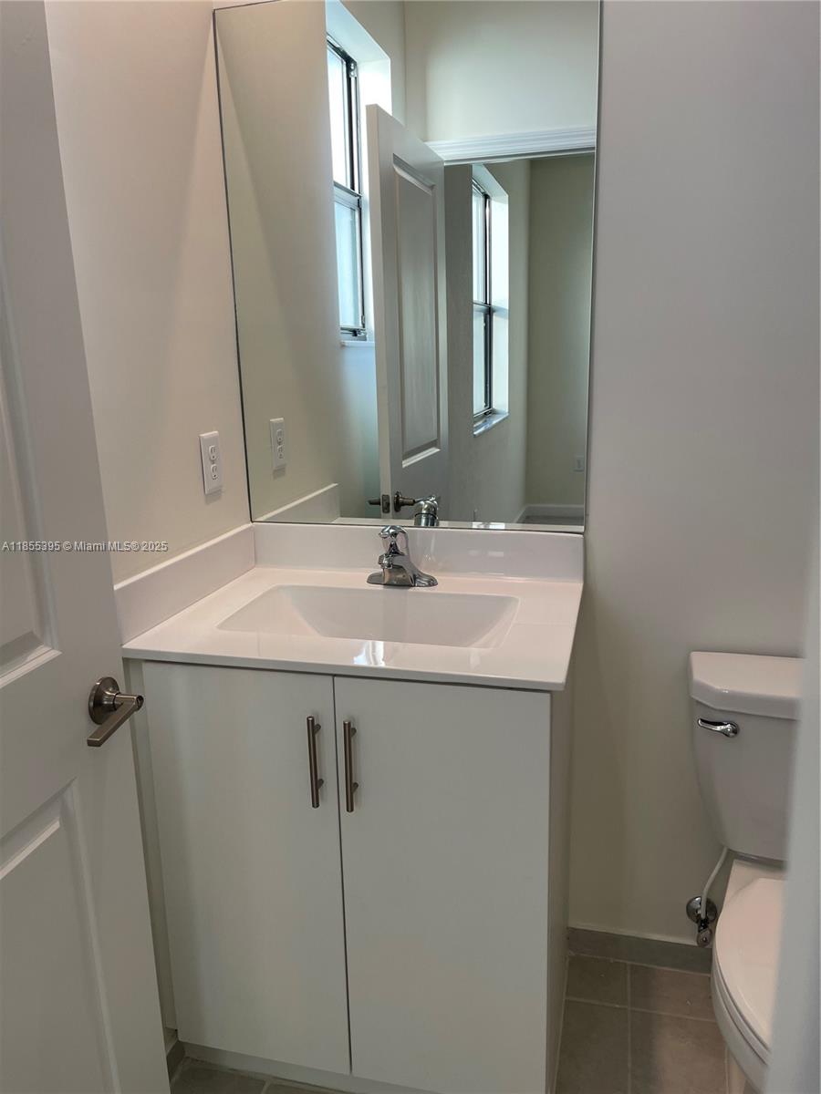 3244 West 114th Terrace, Unit 3244 Hialeah, FL 33018 - Photo 14 of 16 a bathroom with a sink toilet and mirror