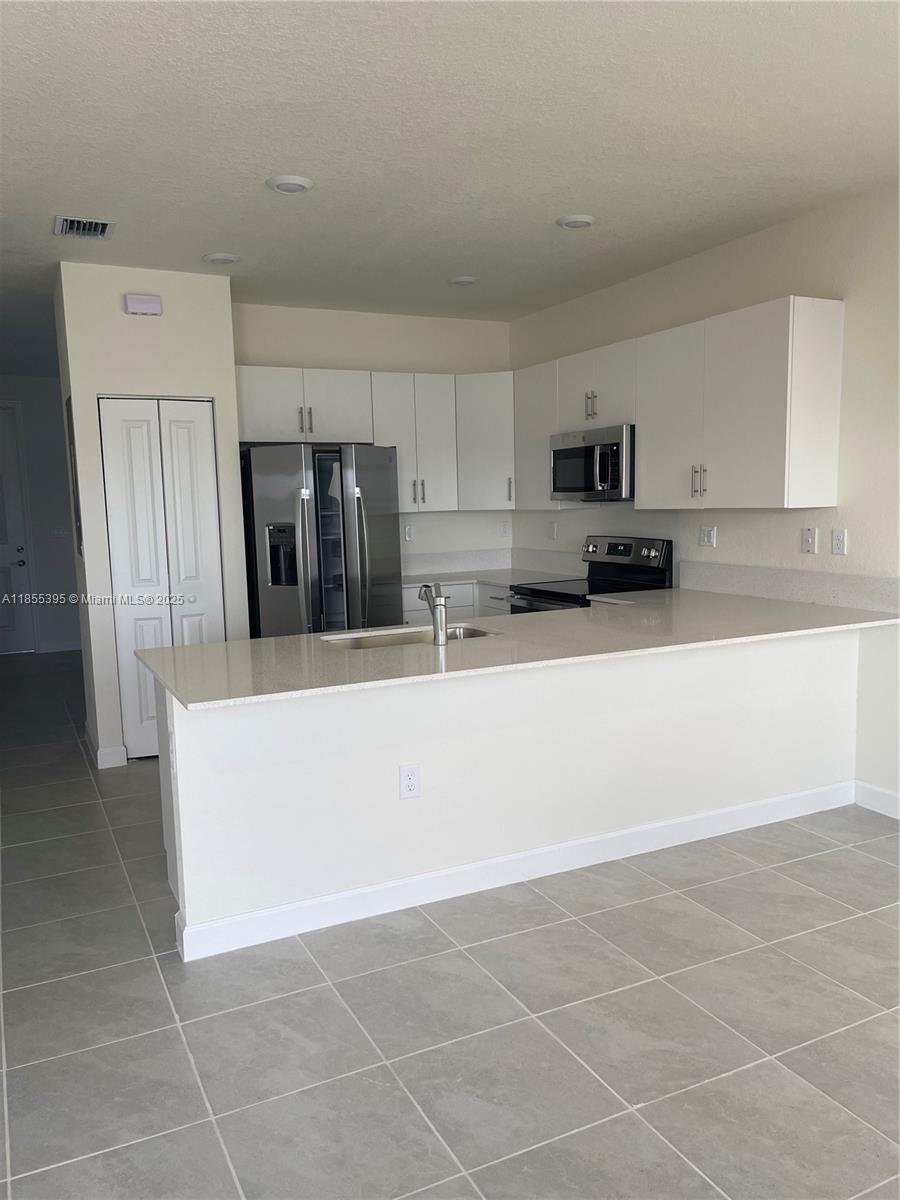 3244 West 114th Terrace, Unit 3244 Hialeah, FL 33018 - Photo 7 of 16 a kitchen with stainless steel appliances a refrigerator sink and microwave