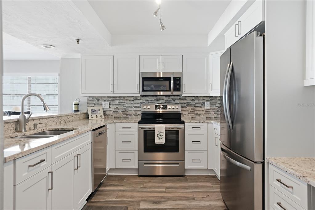 16330 Gulf Boulevard, Unit 306 Redington Beach, FL 33708 - Photo 11 of 39 a kitchen with white cabinets and stainless steel appliances