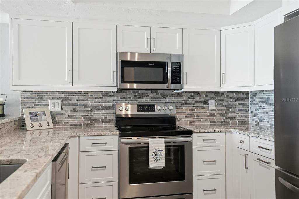 16330 Gulf Boulevard, Unit 306 Redington Beach, FL 33708 - Photo 15 of 39 a kitchen with granite countertop white cabinets and stainless steel appliances