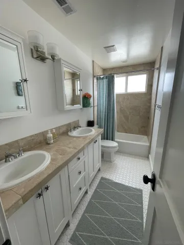a bathroom with a double vanity sink toilet mirror and shower