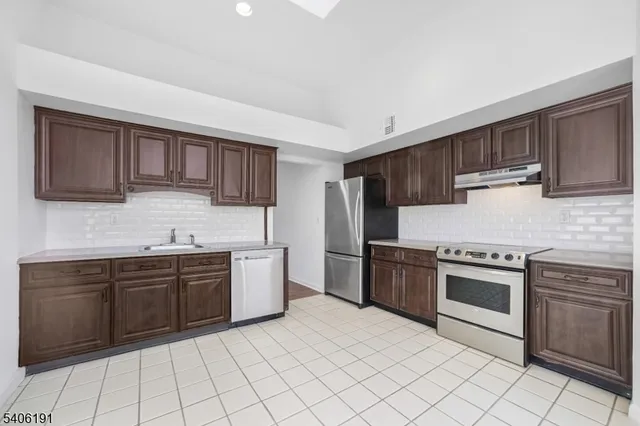 a kitchen with stainless steel appliances granite countertop a stove top oven sink and cabinets