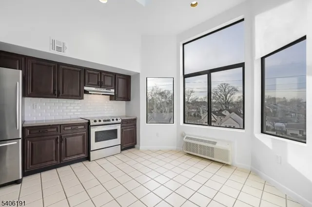 a kitchen with stainless steel appliances granite countertop a stove top oven a sink and a refrigerator