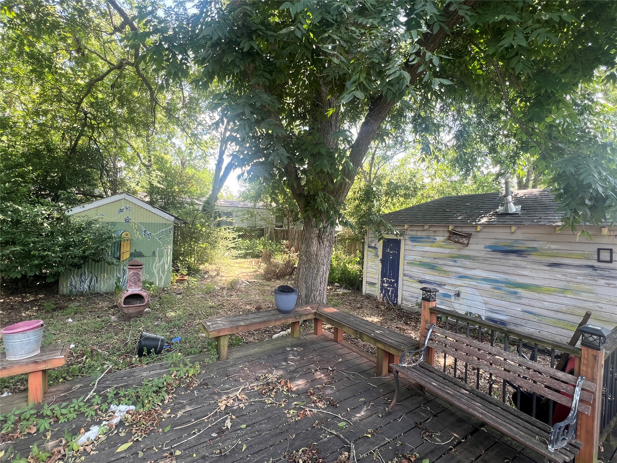 107 West 7th Street Elgin, TX 78621 - Photo 7 of 11 An inviting backyard oasis offers ample space for recreation, complete with a deck and mature shade trees.