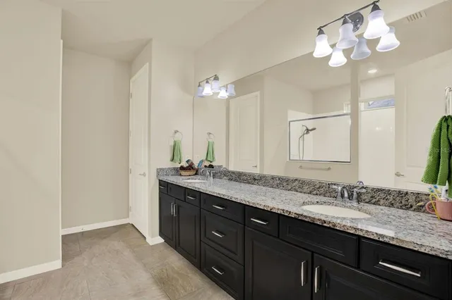 a bathroom with a granite countertop double vanity sink and a mirror