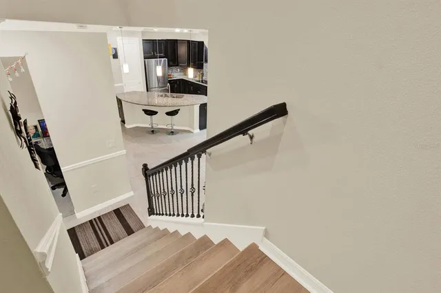 a view of a hallway to a bedroom with wooden floor and stairs