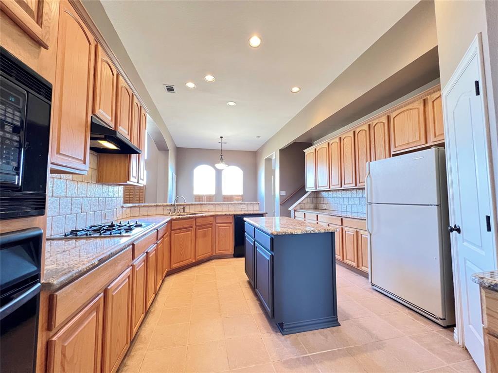 7517 Rodeo Drive Denton, TX 76208 - Photo 12 of 30 a kitchen with stainless steel appliances granite countertop a stove top oven a refrigerator a sink and dishwasher with wooden cabinets