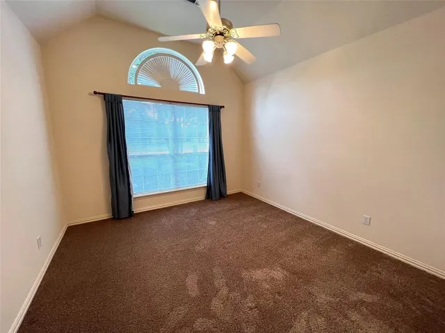 an empty room with a ceiling fan and a window