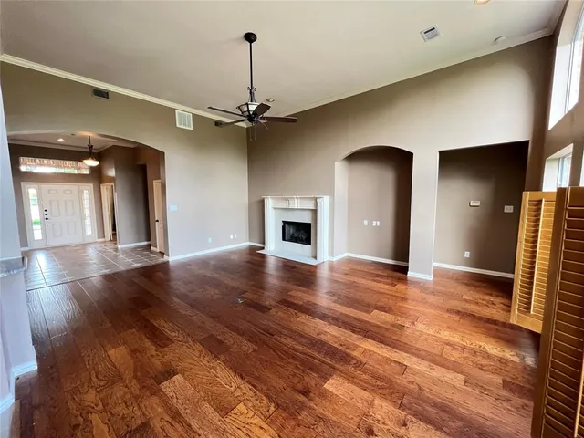 a view of a livingroom with a fireplace a ceiling fan and wooden floor