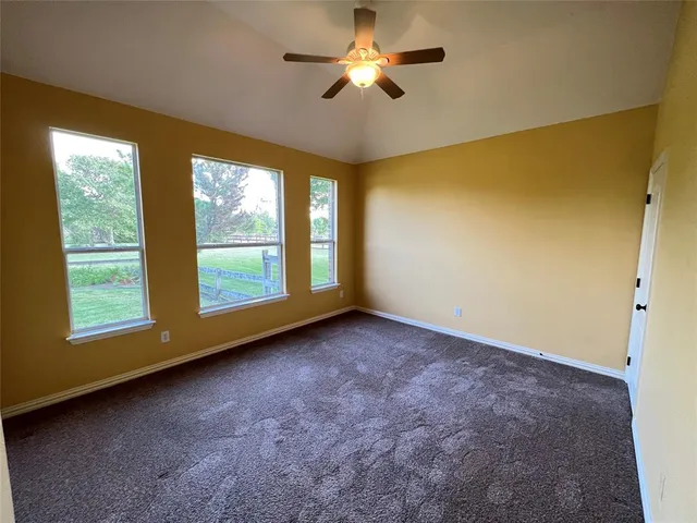 a view of empty room with window and ceiling fan