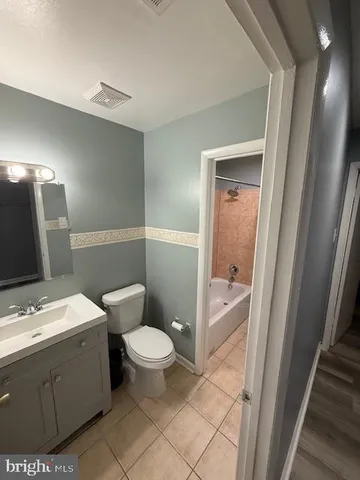 a bathroom with a toilet a sink a tub and mirror