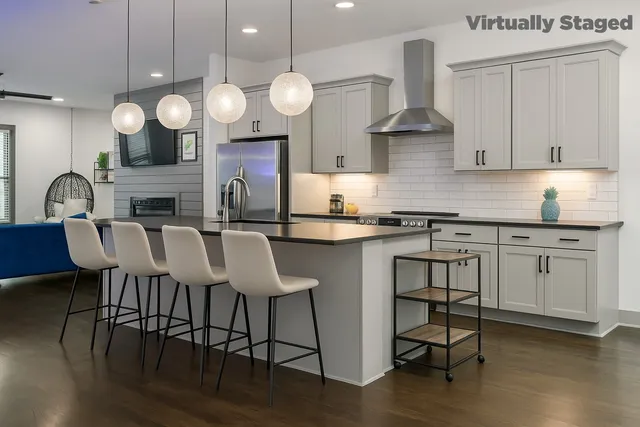 an open kitchen with granite countertop a stove a oven a dining table and chairs with wooden floor