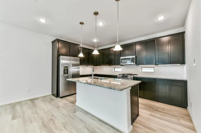 a kitchen with stainless steel appliances granite countertop a stove a refrigerator and a sink