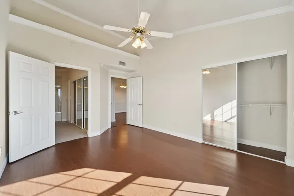 an empty room with windows and chandelier fan