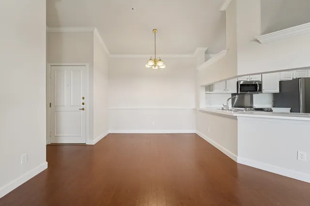 an empty room with wooden floor chandelier fan and windows