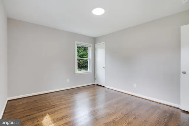 an empty room with wooden floor and window