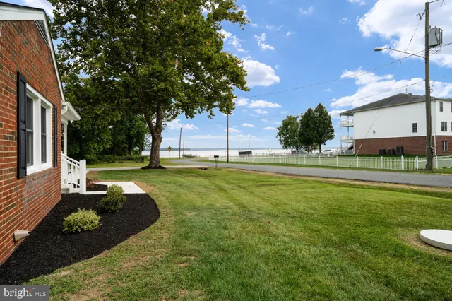 a view of a white house with a big yard and large trees