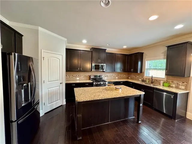 a large kitchen with a large center island stainless steel appliances and cabinets