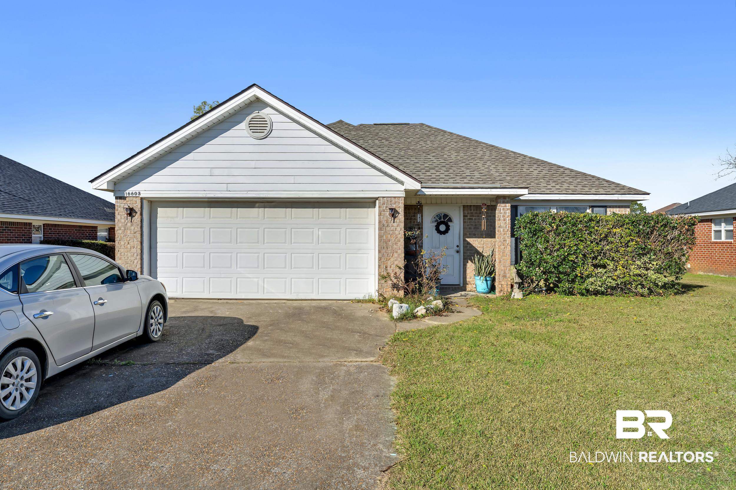 Ranch-style house with concrete driveway, brick siding, a front yard, a shingled roof, and a garage